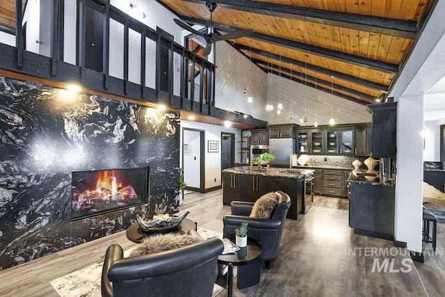 living room featuring hardwood / wood-style floors, wooden ceiling, high vaulted ceiling, a high end fireplace, and beam ceiling