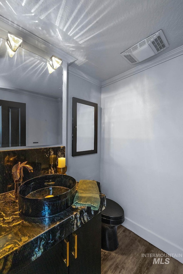 bathroom featuring vanity, a textured ceiling, crown molding, hardwood / wood-style floors, and toilet