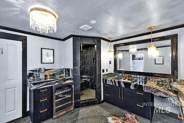 bathroom featuring a textured ceiling, vanity, ornamental molding, and a shower with shower door