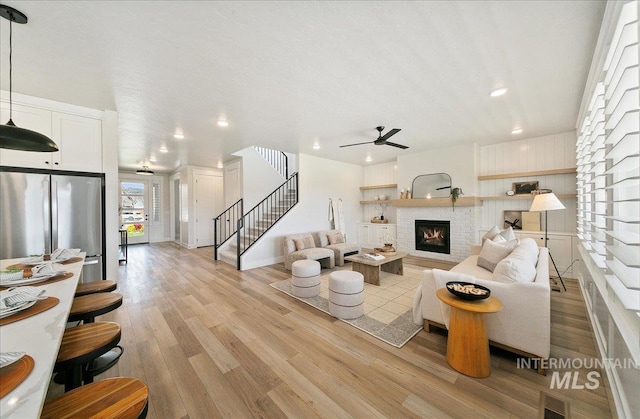 living area with recessed lighting, ceiling fan, light wood-type flooring, and stairs