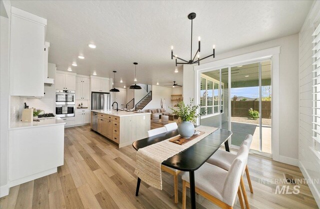 dining space featuring stairway, baseboards, ceiling fan with notable chandelier, recessed lighting, and light wood-style flooring