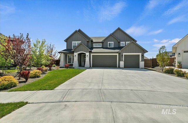 craftsman-style home with fence, a front lawn, a garage, board and batten siding, and concrete driveway