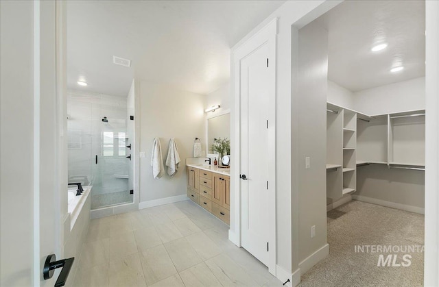 full bath with visible vents, a shower stall, vanity, baseboards, and a spacious closet