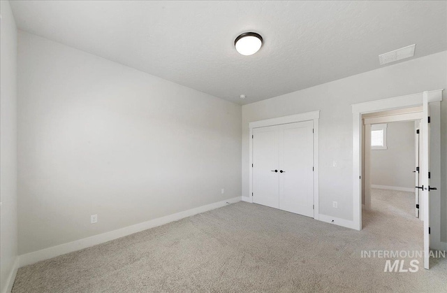 unfurnished bedroom featuring a closet, baseboards, carpet flooring, and a textured ceiling