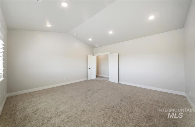 empty room featuring carpet floors, baseboards, recessed lighting, and lofted ceiling