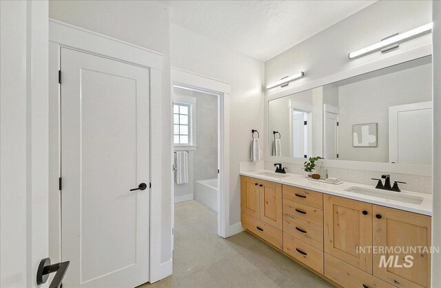 full bathroom with double vanity, a bathtub, a sink, and tile patterned flooring