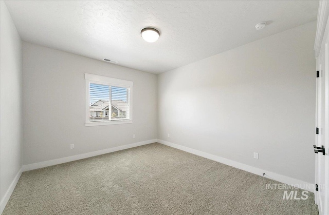 carpeted empty room featuring visible vents, a textured ceiling, and baseboards