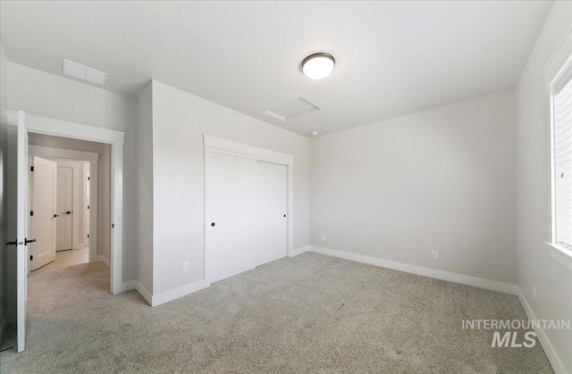 unfurnished bedroom with baseboards, light carpet, a closet, and visible vents