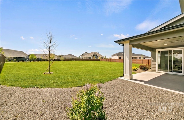 view of yard featuring a patio, fence, and a residential view
