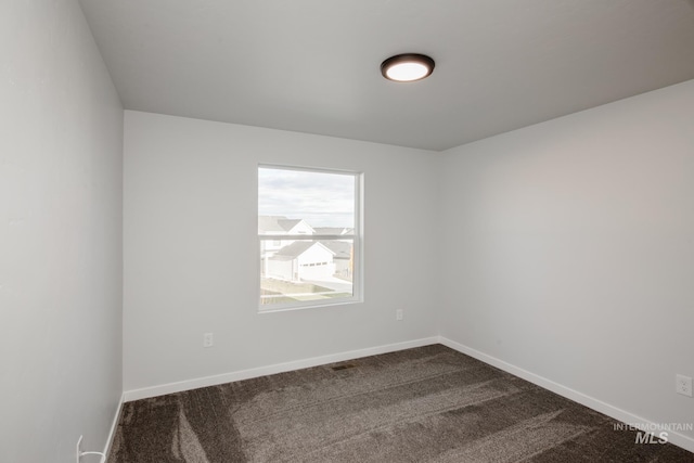 unfurnished room with dark colored carpet and baseboards