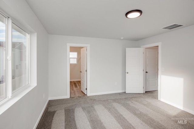 unfurnished bedroom with carpet, visible vents, and baseboards