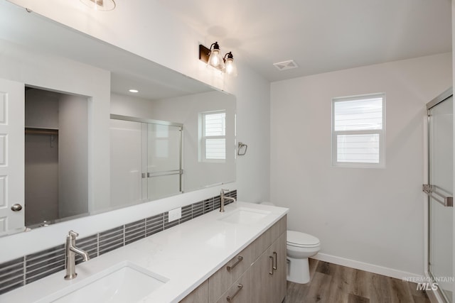 full bathroom with toilet, wood finished floors, a stall shower, and a sink