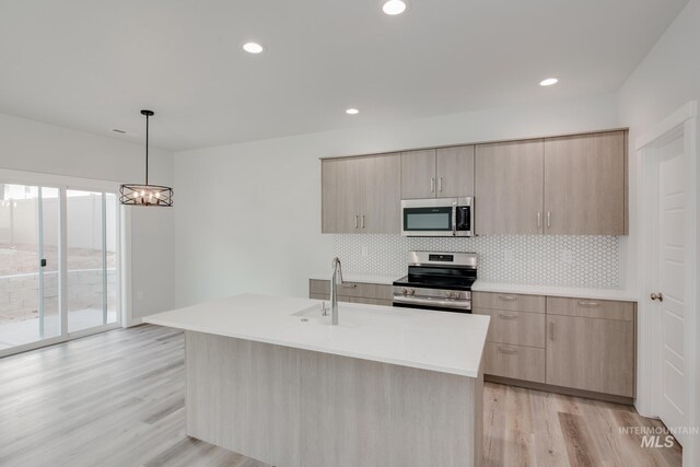 kitchen featuring stainless steel appliances, light wood-style flooring, decorative backsplash, light brown cabinets, and modern cabinets