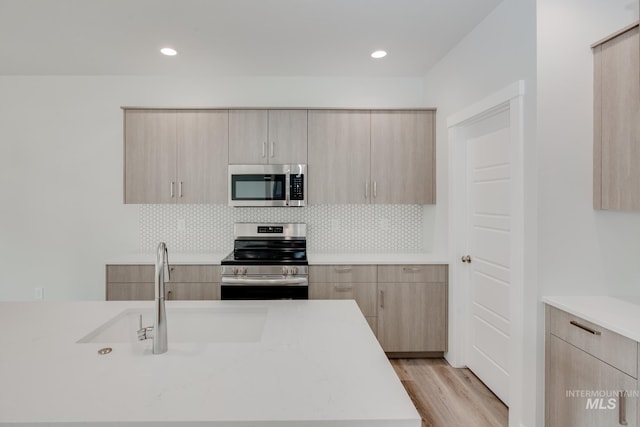 kitchen with light wood-style floors, appliances with stainless steel finishes, modern cabinets, and light brown cabinetry
