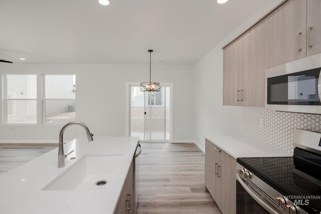 kitchen with a sink, light brown cabinetry, stainless steel appliances, light countertops, and tasteful backsplash