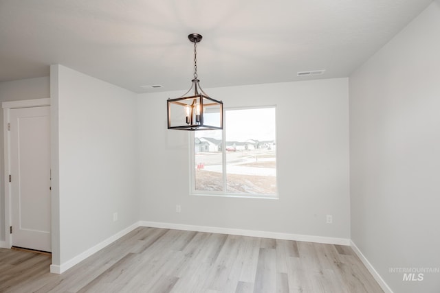 unfurnished dining area with light hardwood / wood-style flooring and a chandelier