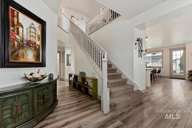 stairs with baseboards, a high ceiling, and wood finished floors