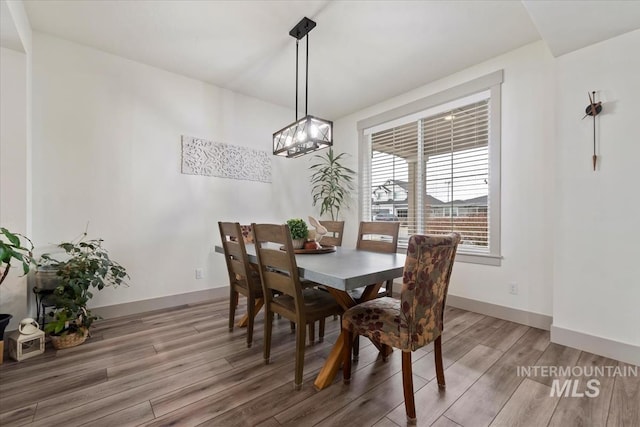 dining room with baseboards, an inviting chandelier, and light wood-style floors