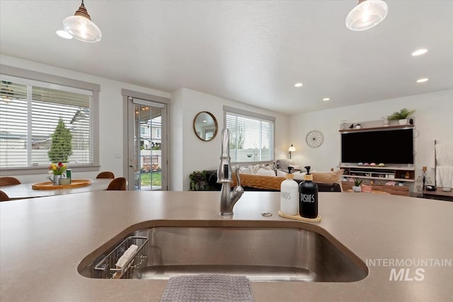 kitchen with a sink, open floor plan, recessed lighting, and decorative light fixtures