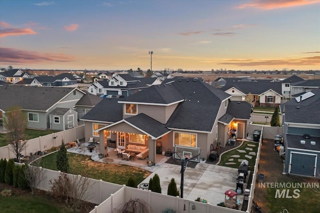 back of house at dusk featuring a residential view, a fenced backyard, and an outdoor hangout area