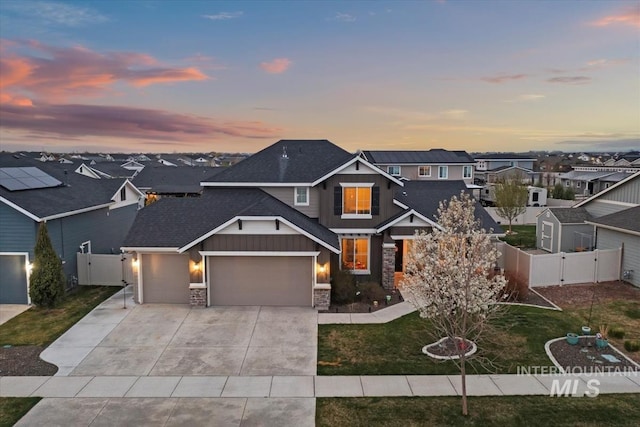 view of front of property featuring board and batten siding, fence, a gate, a garage, and a residential view