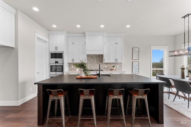 6536 W Flathead Lake St, Eagle, ID 83616 - kitchen with appliances with stainless steel finishes, dark countertops, dark wood-style flooring, a center island with sink, and tasteful backsplash