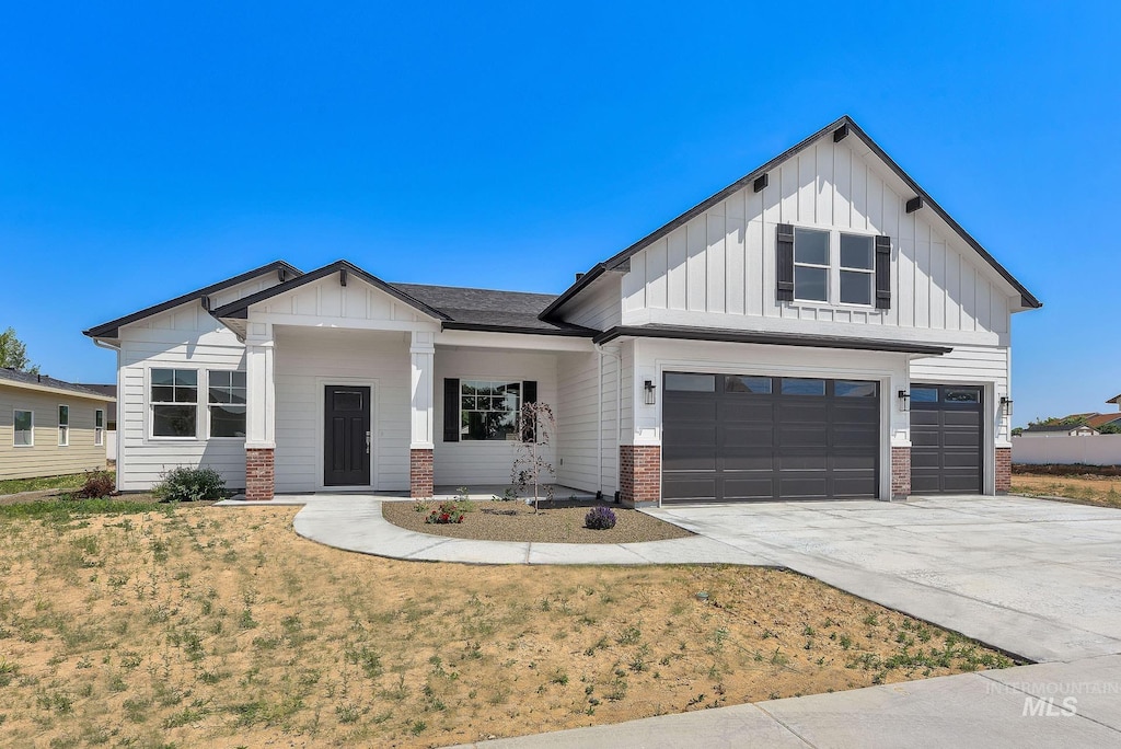 modern farmhouse with a garage, driveway, brick siding, board and batten siding, and a front yard