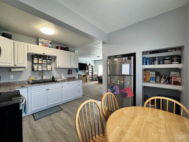 713 California St, Gooding, ID 83330 - kitchen with freestanding refrigerator, a sink, a textured ceiling, dark countertops, and light wood finished floors