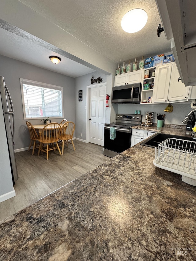 713 California St, Gooding, ID 83330 - kitchen with stainless steel appliances, a sink, light wood-style floors, a textured ceiling, and open shelves