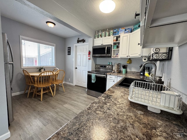 713 California St, Gooding, ID 83330 - kitchen featuring appliances with stainless steel finishes, a textured ceiling, open shelves, white cabinetry, and light wood finished floors