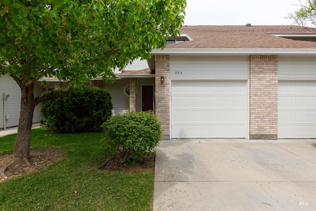 ranch-style home featuring roof with shingles, brick siding, a garage, a front yard, and driveway