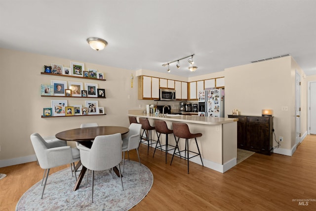 dining room with visible vents, light wood finished floors, and baseboards