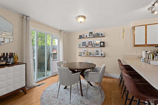 dining area with baseboards, visible vents, and light wood finished floors