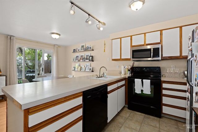 kitchen with light countertops, a peninsula, a sink, and black appliances
