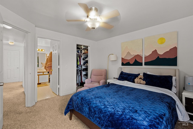 bedroom with connected bathroom, a walk in closet, carpet floors, a ceiling fan, and a closet