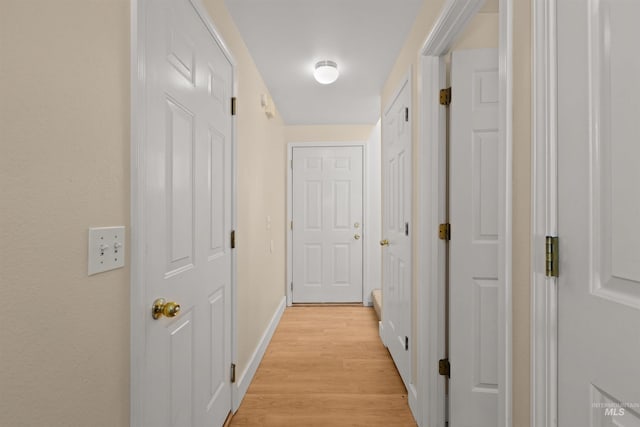 hall featuring baseboards and light wood-type flooring