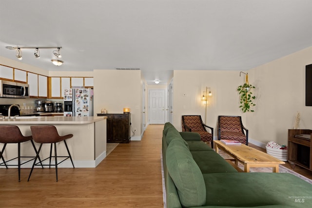 living area featuring light wood-type flooring, baseboards, and visible vents
