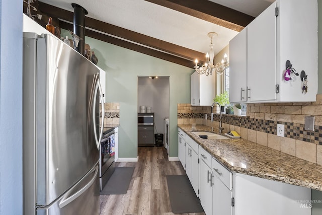 kitchen featuring tasteful backsplash, a sink, lofted ceiling with beams, light wood finished floors, and stainless steel appliances
