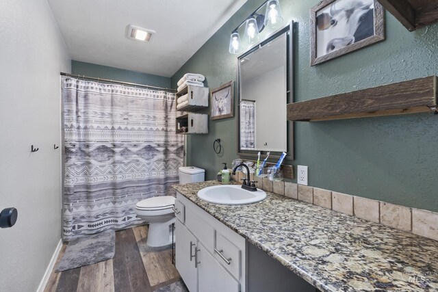 full bath featuring vanity, visible vents, a textured wall, wood finished floors, and toilet