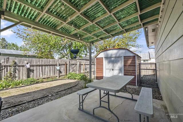 view of patio with outdoor dining area, a fenced backyard, a shed, and an outbuilding