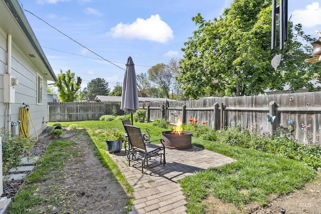 view of yard with a fenced backyard, a fire pit, and a patio area