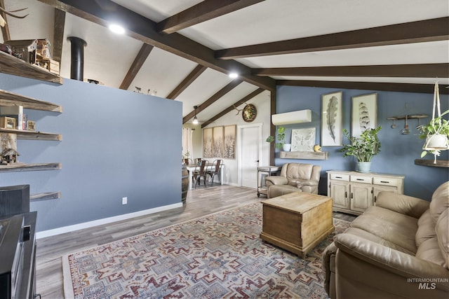 living area with baseboards, lofted ceiling with beams, wood finished floors, and a wall mounted air conditioner