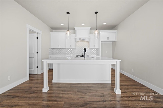 2187 E Hidcote St, Meridian, ID 83642 - kitchen with a kitchen island with sink, light countertops, white cabinets, decorative backsplash, and baseboards