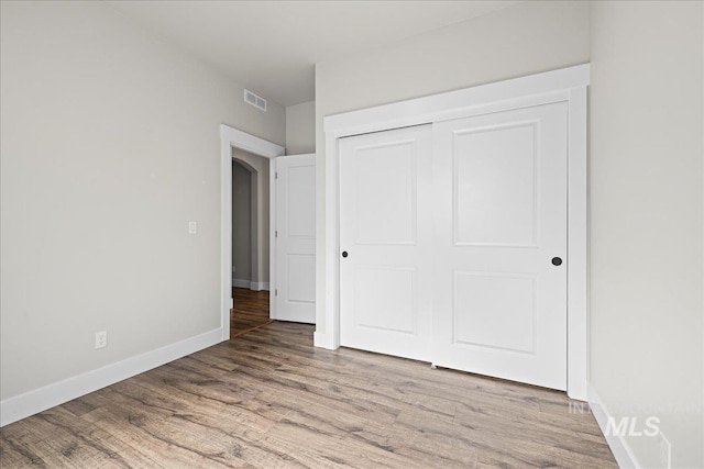 2187 E Hidcote St, Meridian, ID 83642 - unfurnished bedroom featuring wood finished floors, baseboards, a closet, and arched walkways