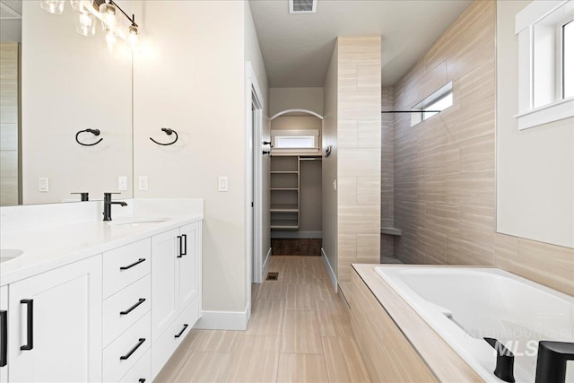 2187 E Hidcote St, Meridian, ID 83642 - full bathroom with tiled tub, double vanity, a tile shower, baseboards, and a walk in closet