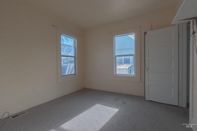 carpeted spare room with plenty of natural light and visible vents