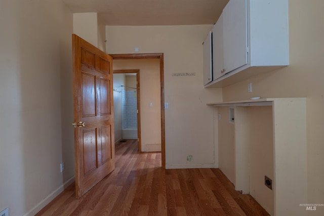 laundry area with baseboards, cabinet space, light wood-style floors, and electric dryer hookup