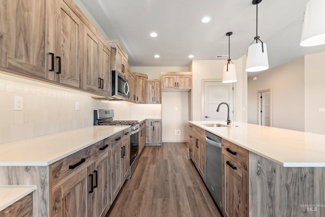 kitchen with recessed lighting, wood finished floors, stainless steel appliances, backsplash, and a sink