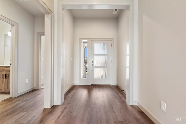 doorway to outside featuring baseboards, visible vents, and wood finished floors