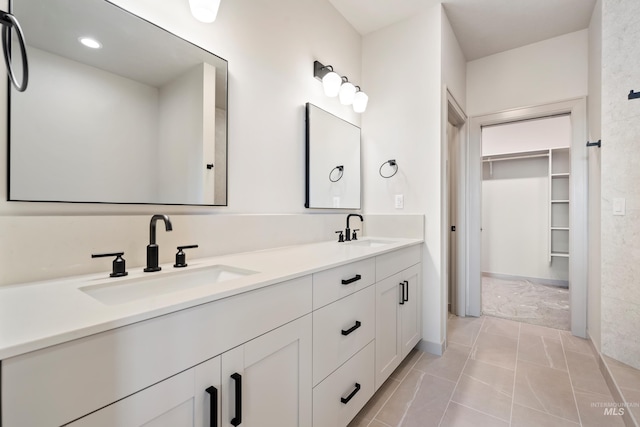 bathroom with a walk in closet, tile patterned floors, double vanity, and a sink